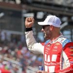 NASCAR driver celebrating with fans in the grandstands behind
