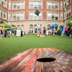 Cornhole board in the foreground at an outdoor event