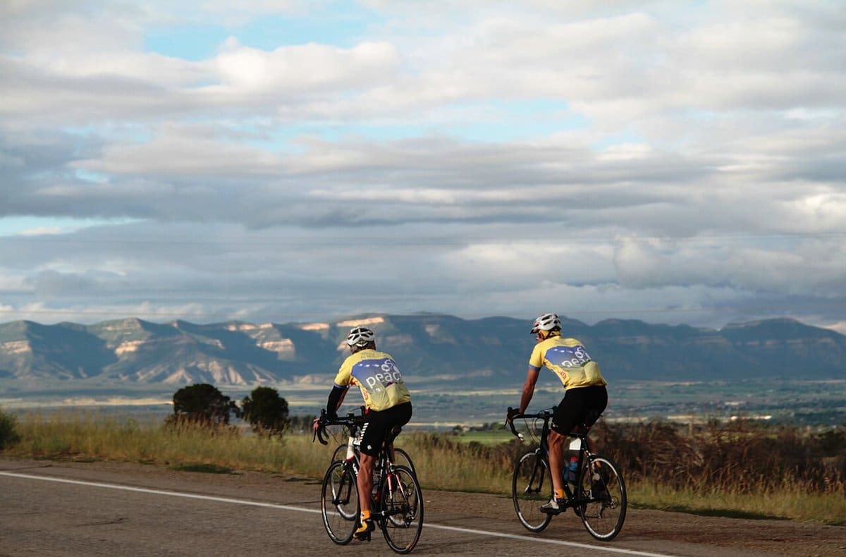 Two road cyclists riding with a mountain view