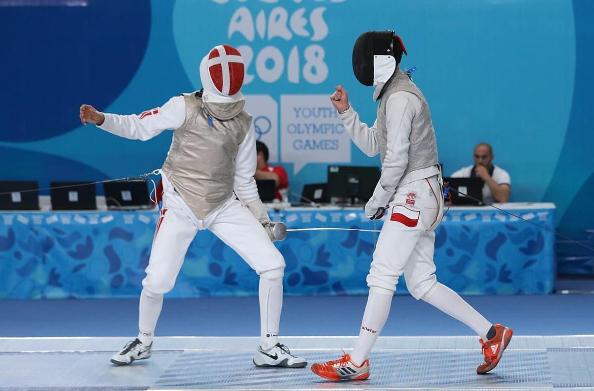 Two young women fencers facing off at a youth tournament