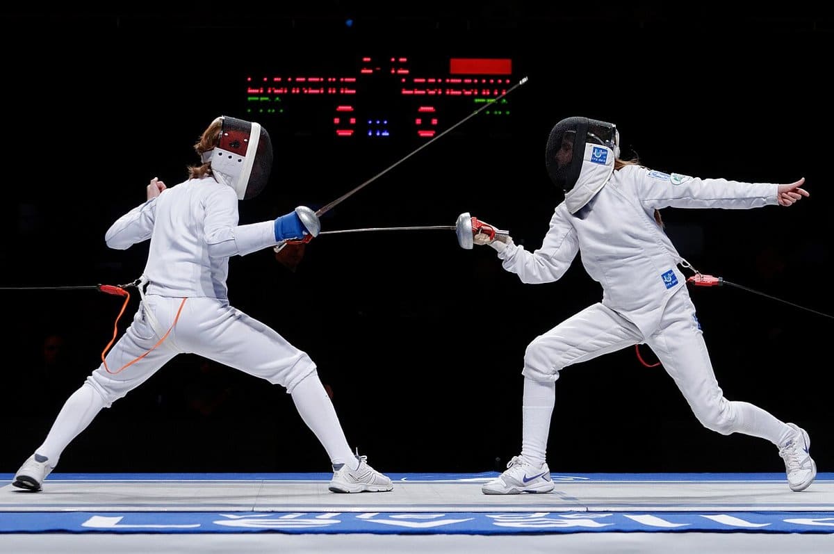 Fencers circling each other on a lit strip