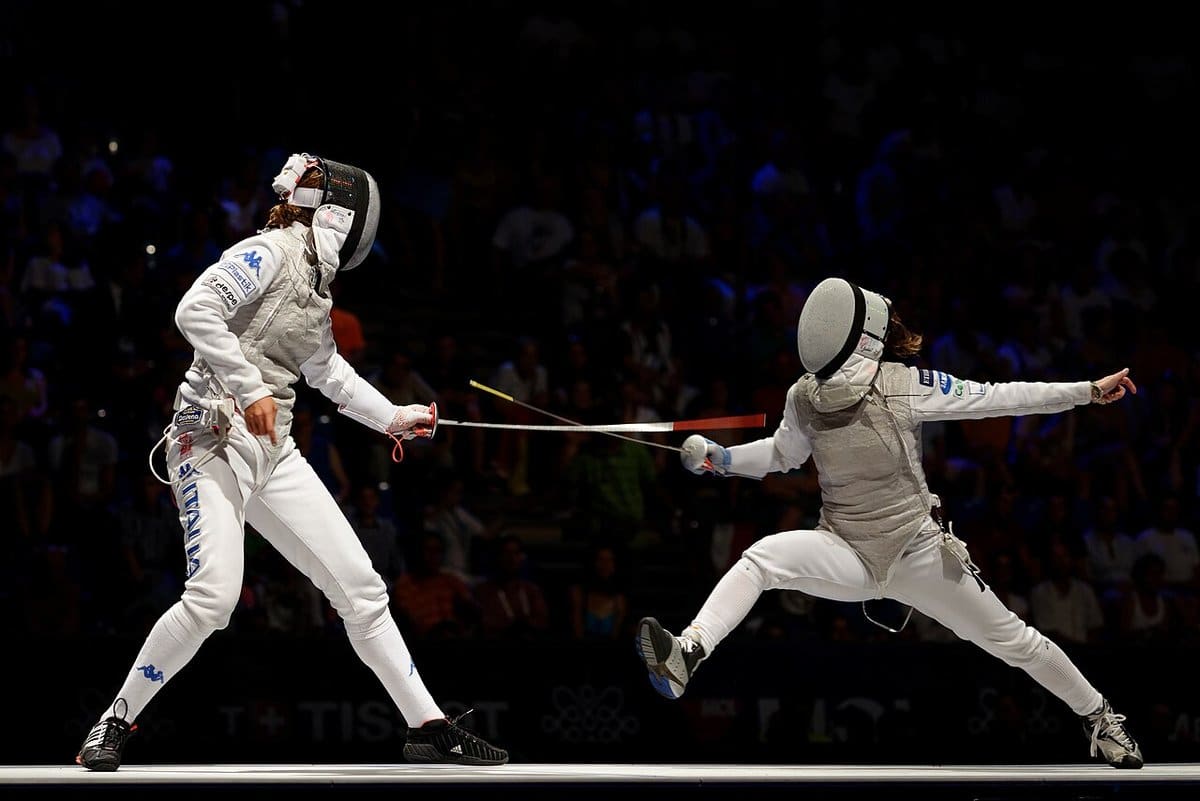 Foil fencers trading attacks under the arena lights