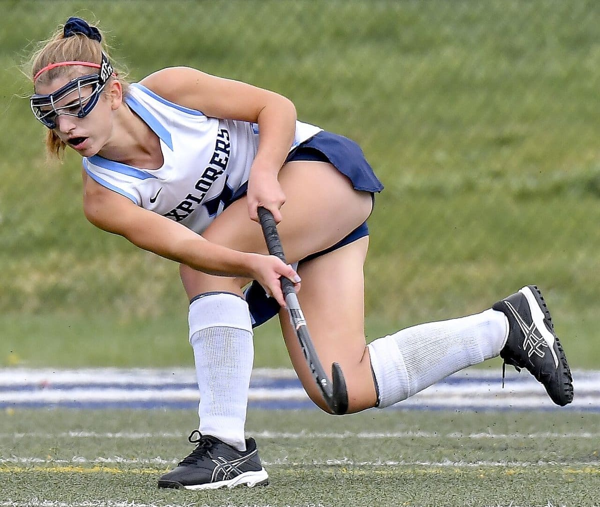 Field hockey player in goggles lunging for the ball