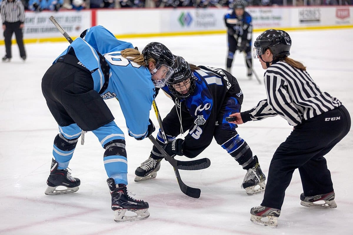 Women hockey players lined up for a faceoff