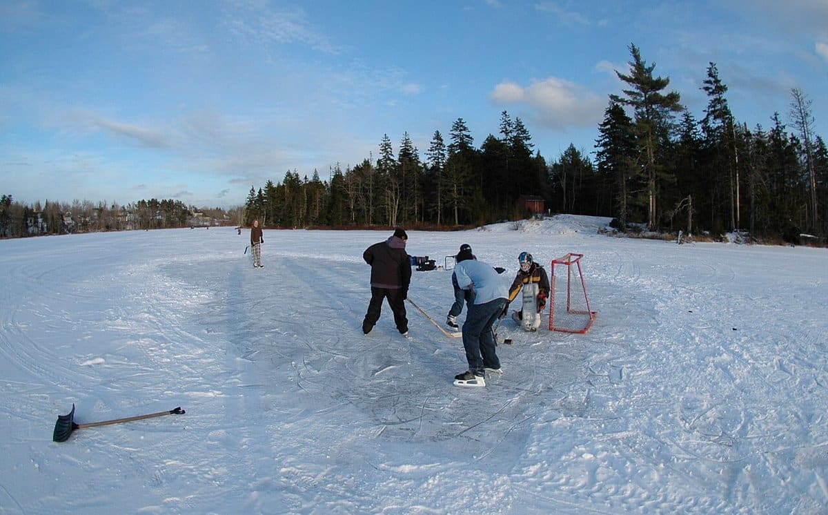 Friends playing pond hockey on a frozen lake