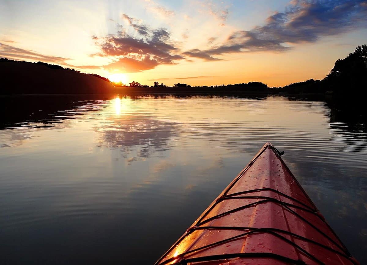 View from the bow of a kayak at sunset on a lake