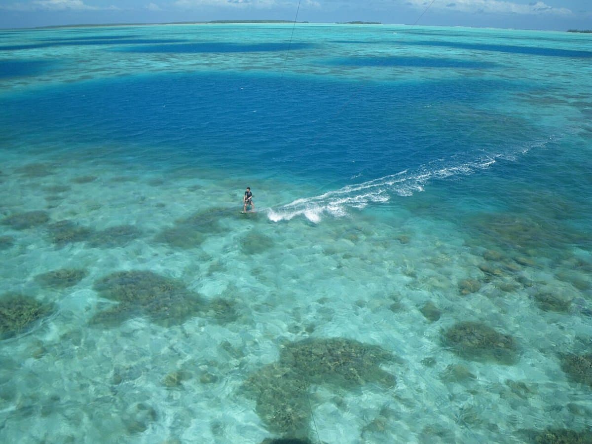 Kitesurfer gliding across a turquoise tropical lagoon