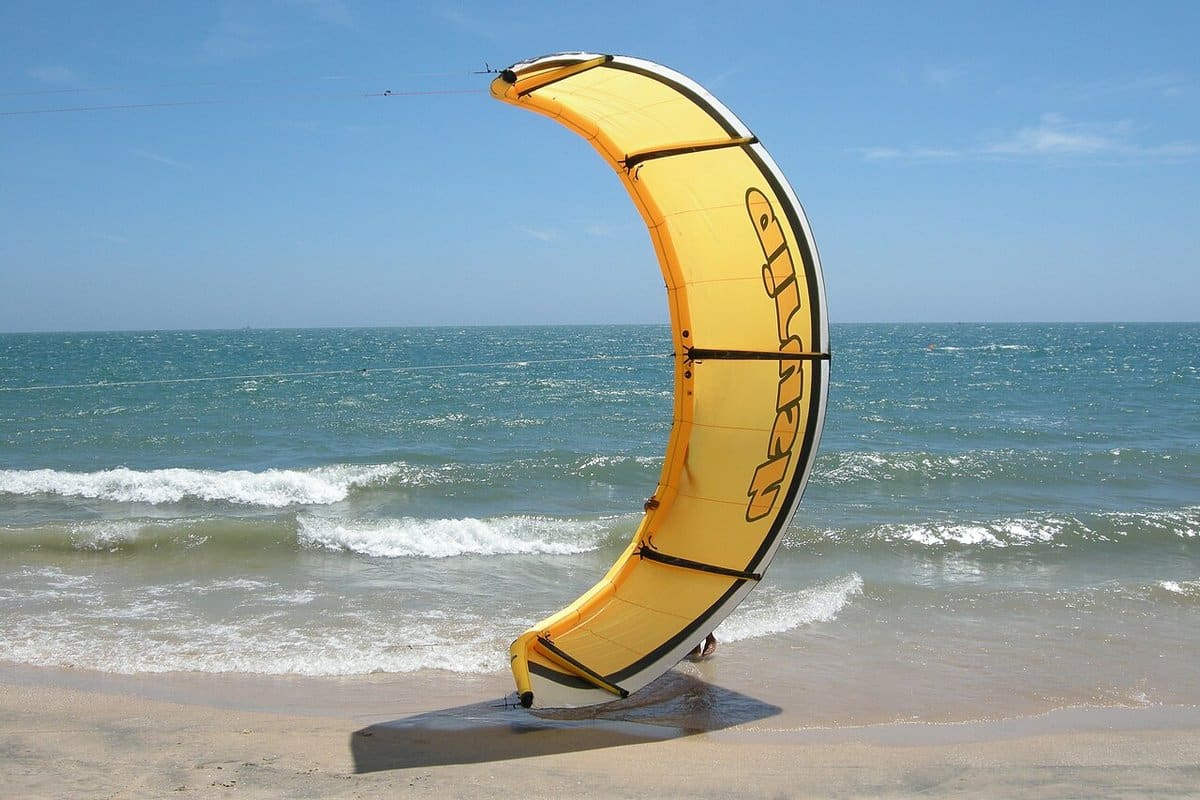 Yellow kite resting on the sand at a windy beach