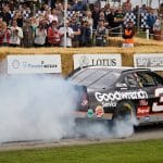 Classic NASCAR stock car doing a burnout in front of a crowd