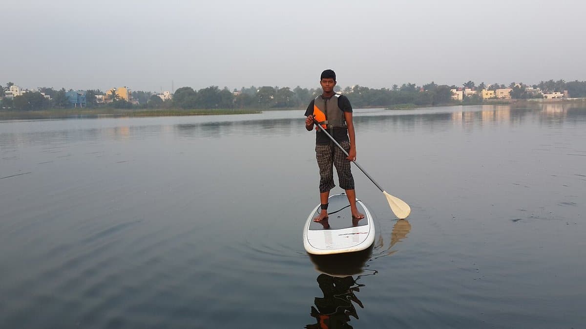 Paddleboarder standing on a calm lake at dusk