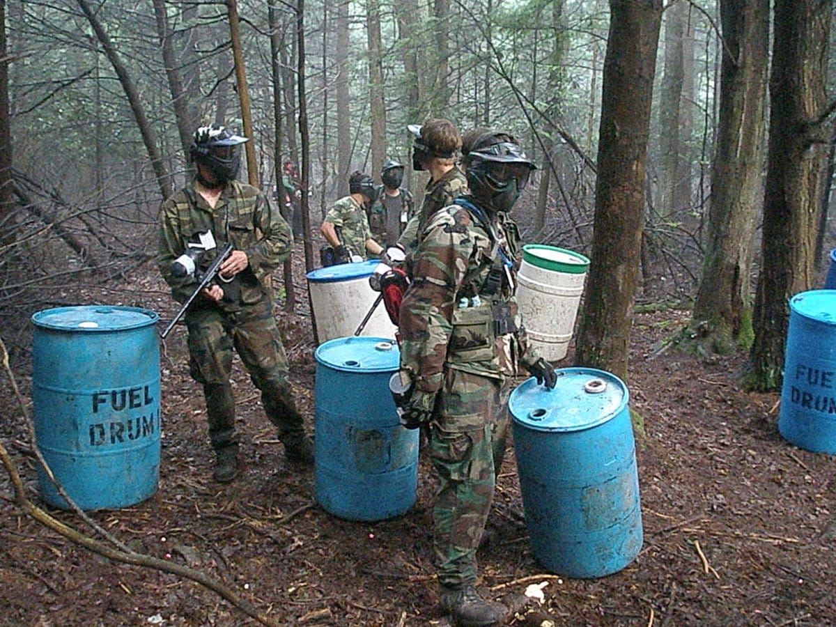 Scenario paintball players in masks moving through the woods