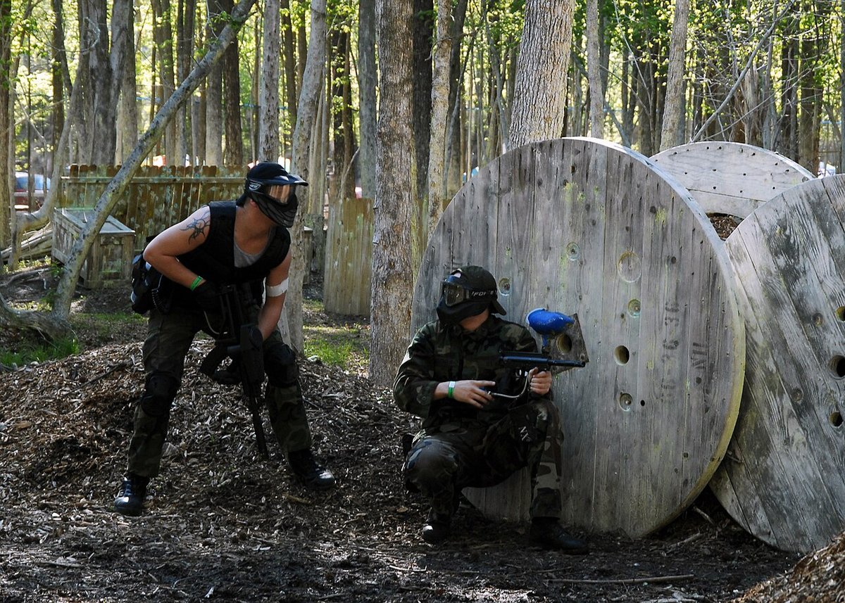 Two woodsball players taking cover behind cable spools