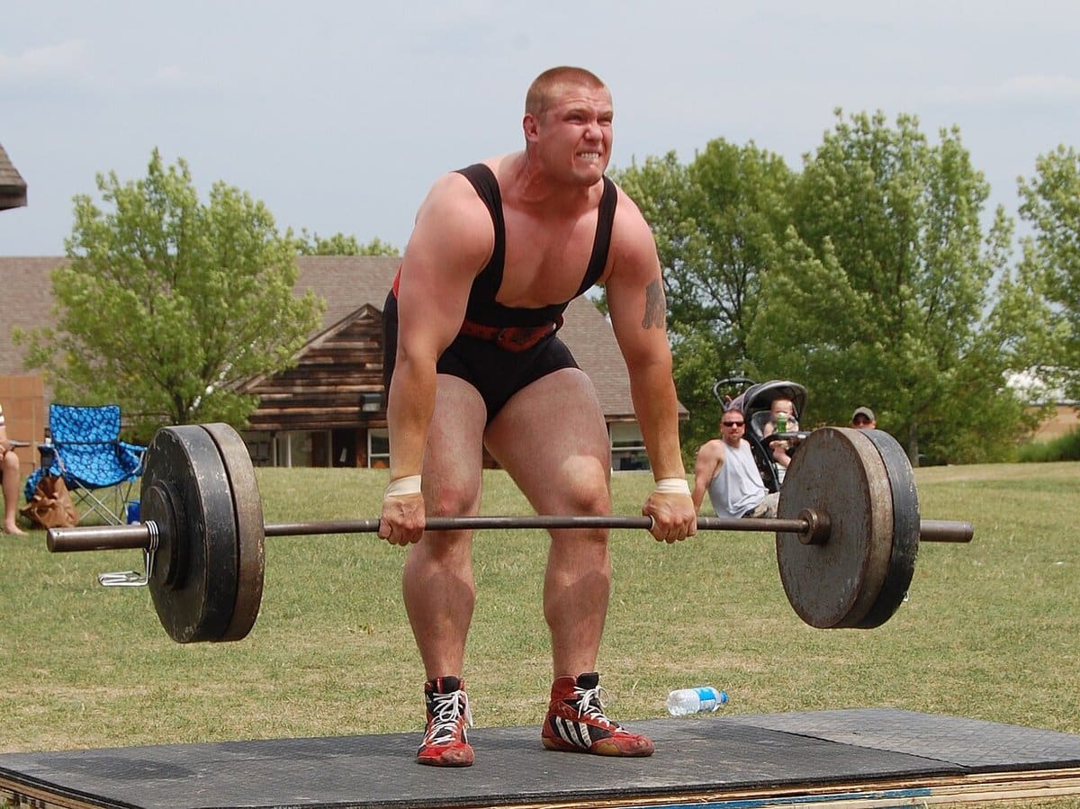 Powerlifter locking out a heavy deadlift outdoors