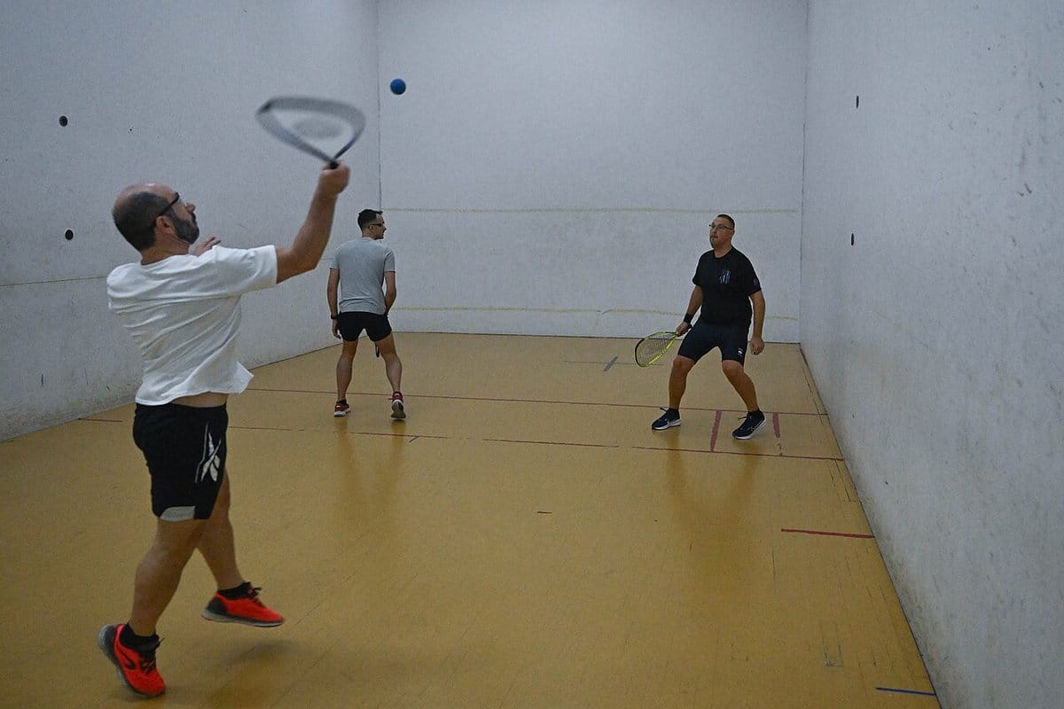 Players in the middle of a rally on an indoor racquetball court