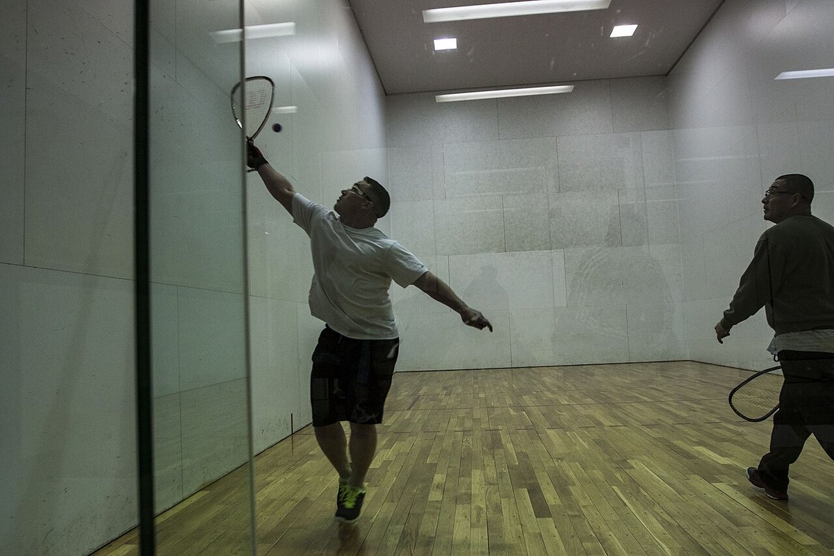 Player reaching high for an overhead shot on a glass court