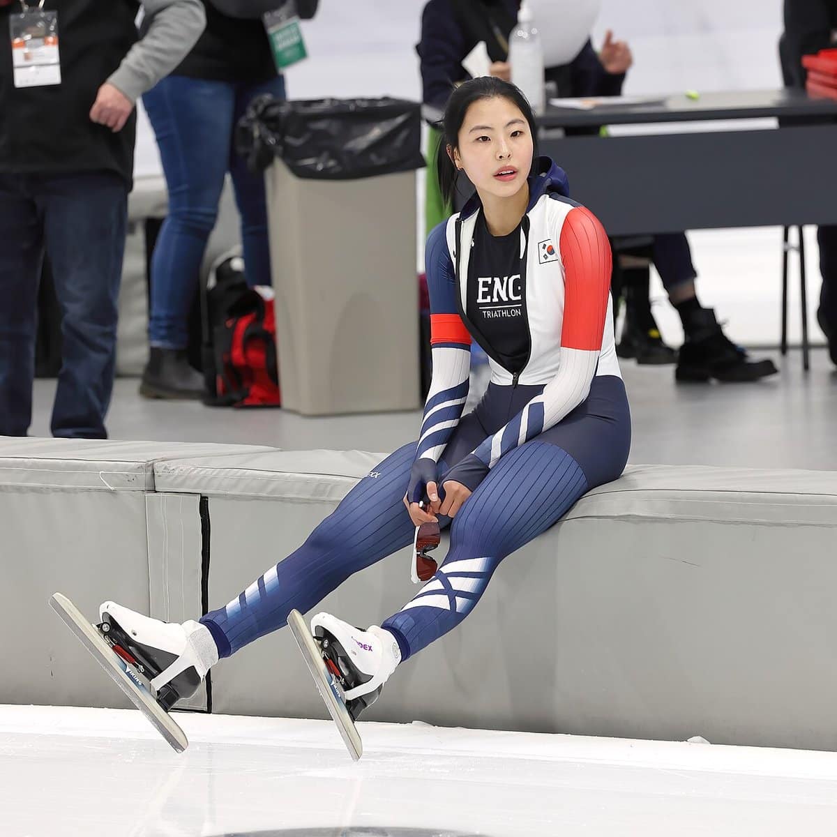 Speed skater resting rinkside in her suit