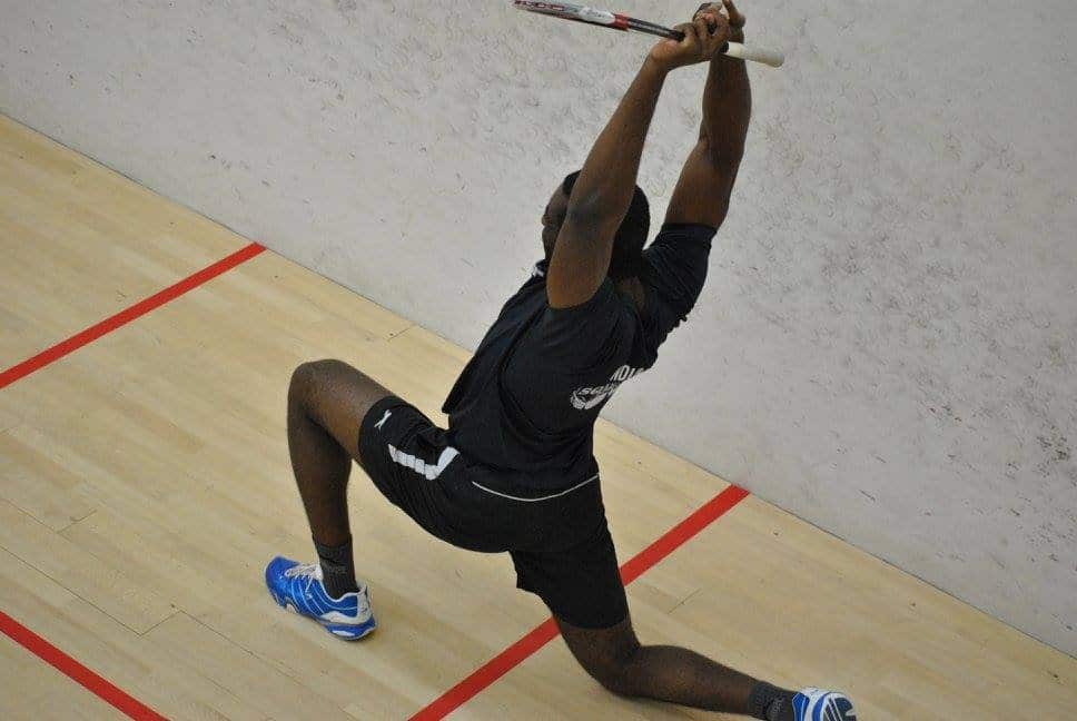 Squash player stretching low on the court
