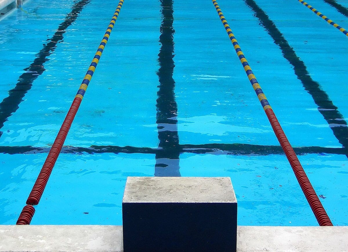 Empty competition pool with lane ropes and a starting block