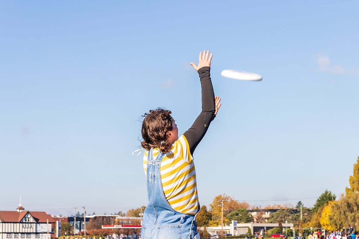 Child reaching up to catch a flying disc