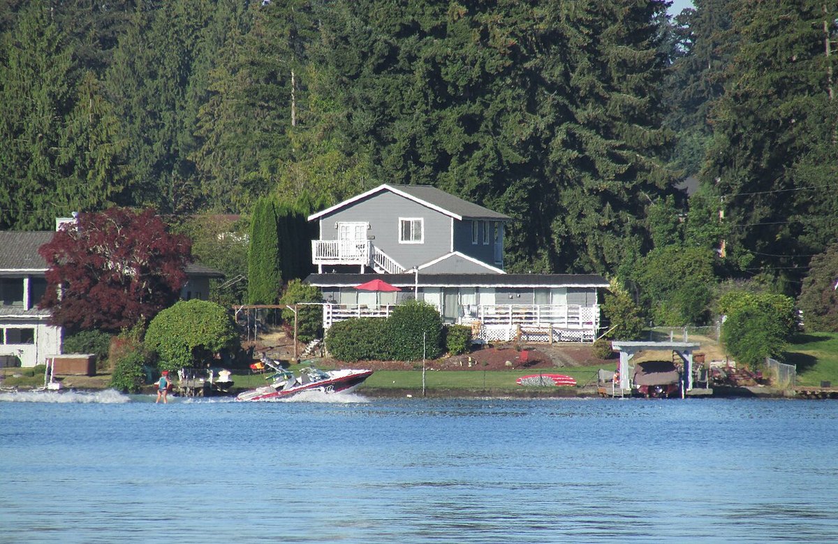 Ski boat cruising past lake houses on a sunny day