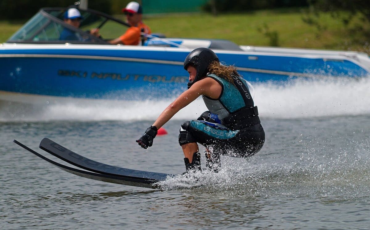 Woman water skier crouching low behind the boat