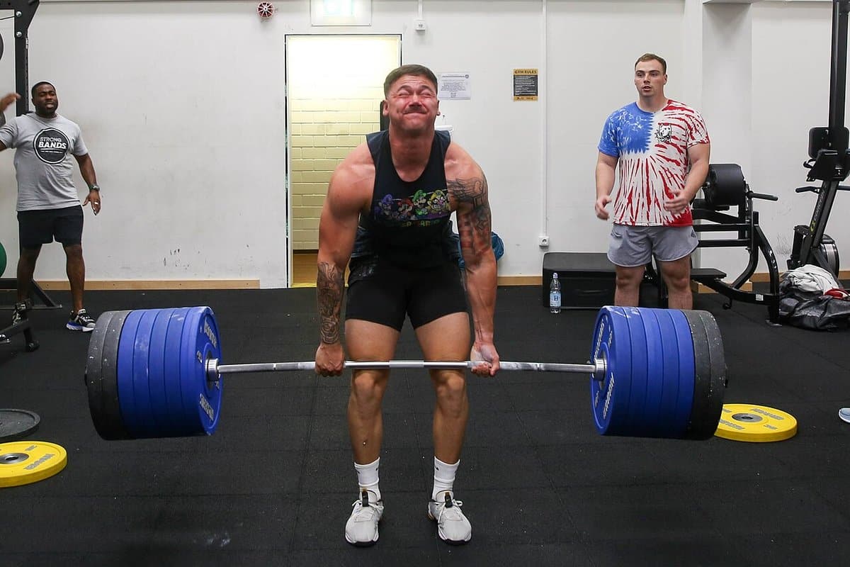 Lifter grinding out a heavy deadlift in a busy gym