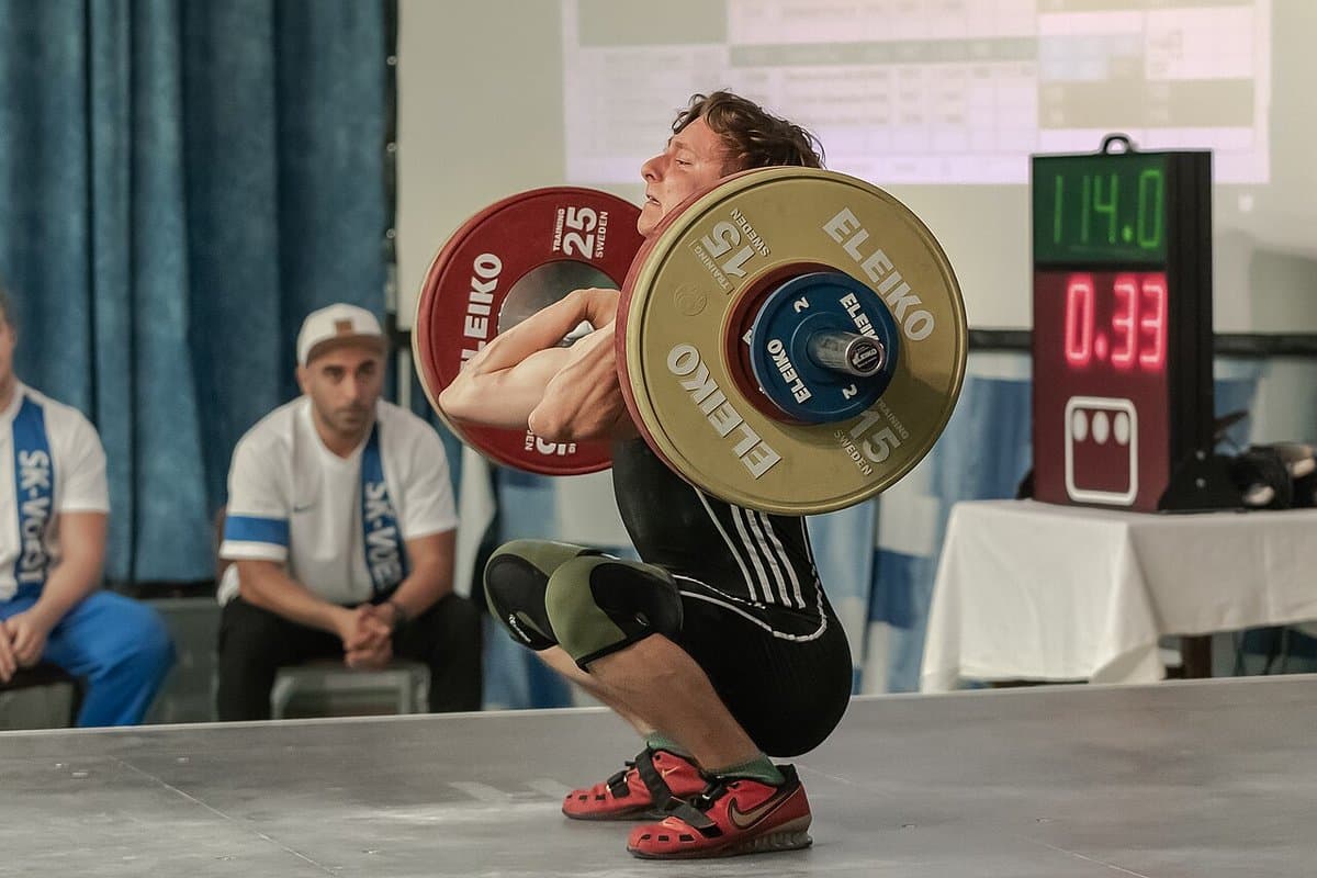 Lifter racking a heavy clean in front of the judges