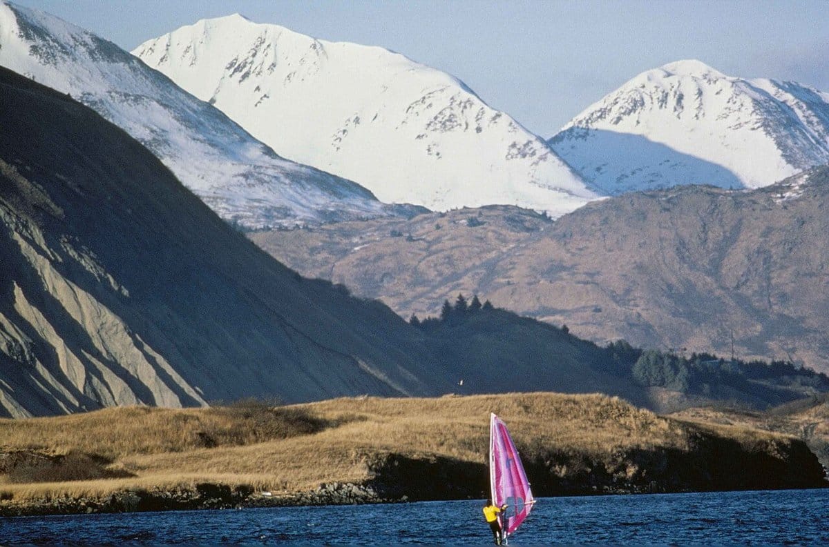 Windsurfer on a mountain lake below snowy peaks