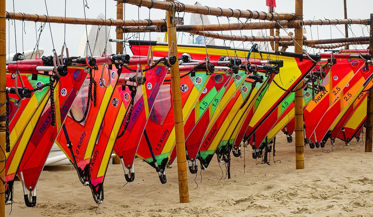 Colorful windsurf sails lined up on a beach rack